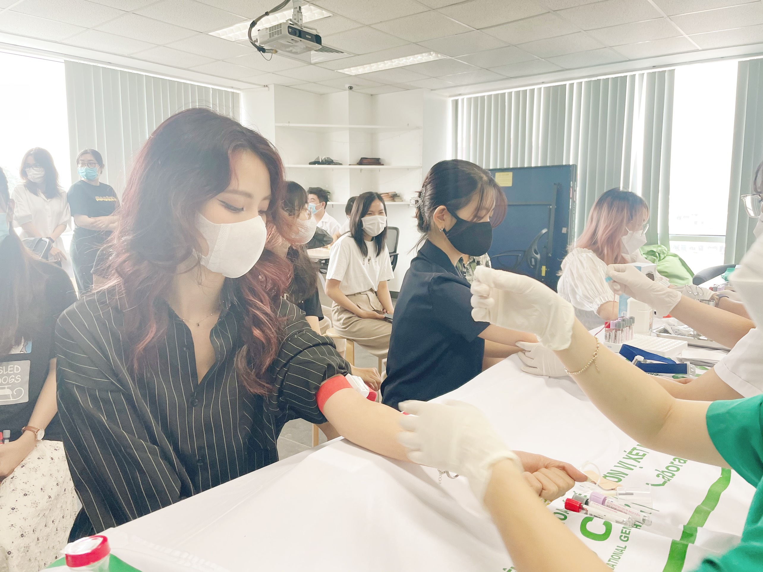 Women wearing masks donating blood in a medical blood donation drive