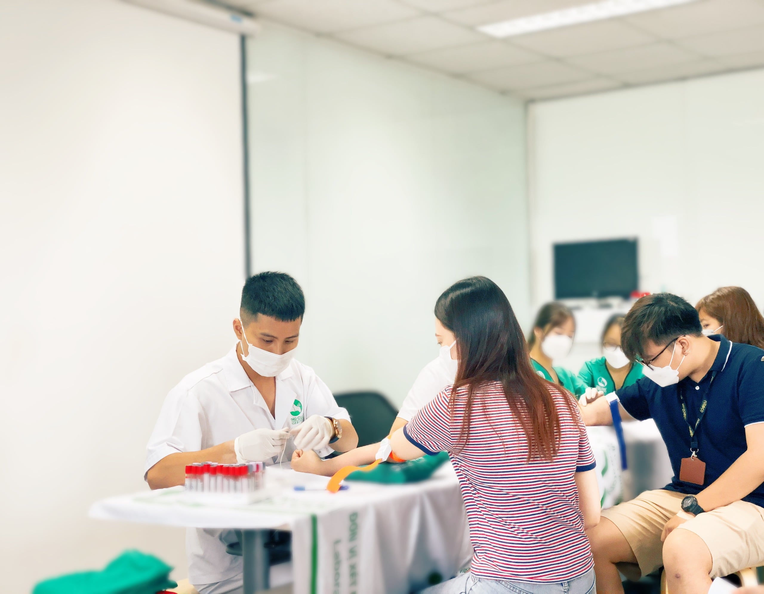 Medical staff drawing blood samples from seated patients during health screening