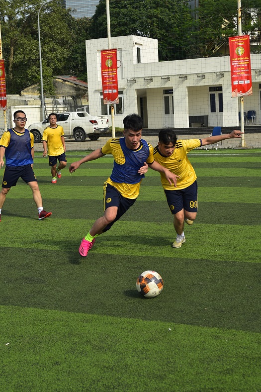 Young men competing intensely for the soccer ball on a green football field