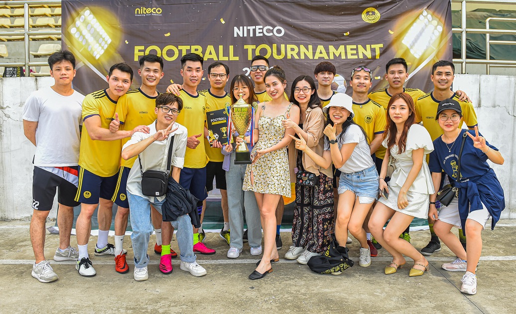 Group of young people celebrating victory at Niteco Football Tournament with trophy
