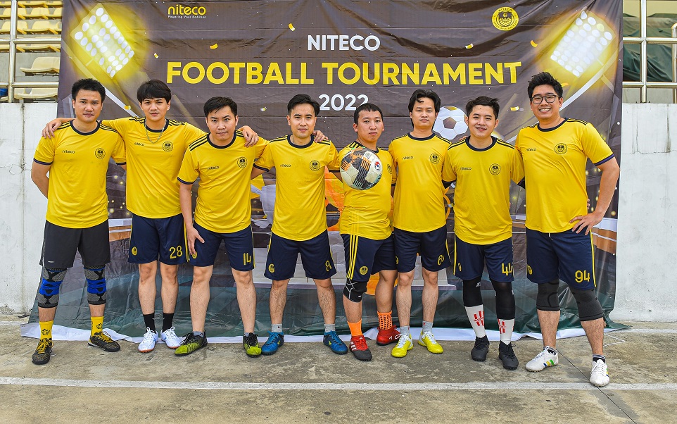 Niteco football tournament 2022 team in yellow jerseys posing with a soccer ball