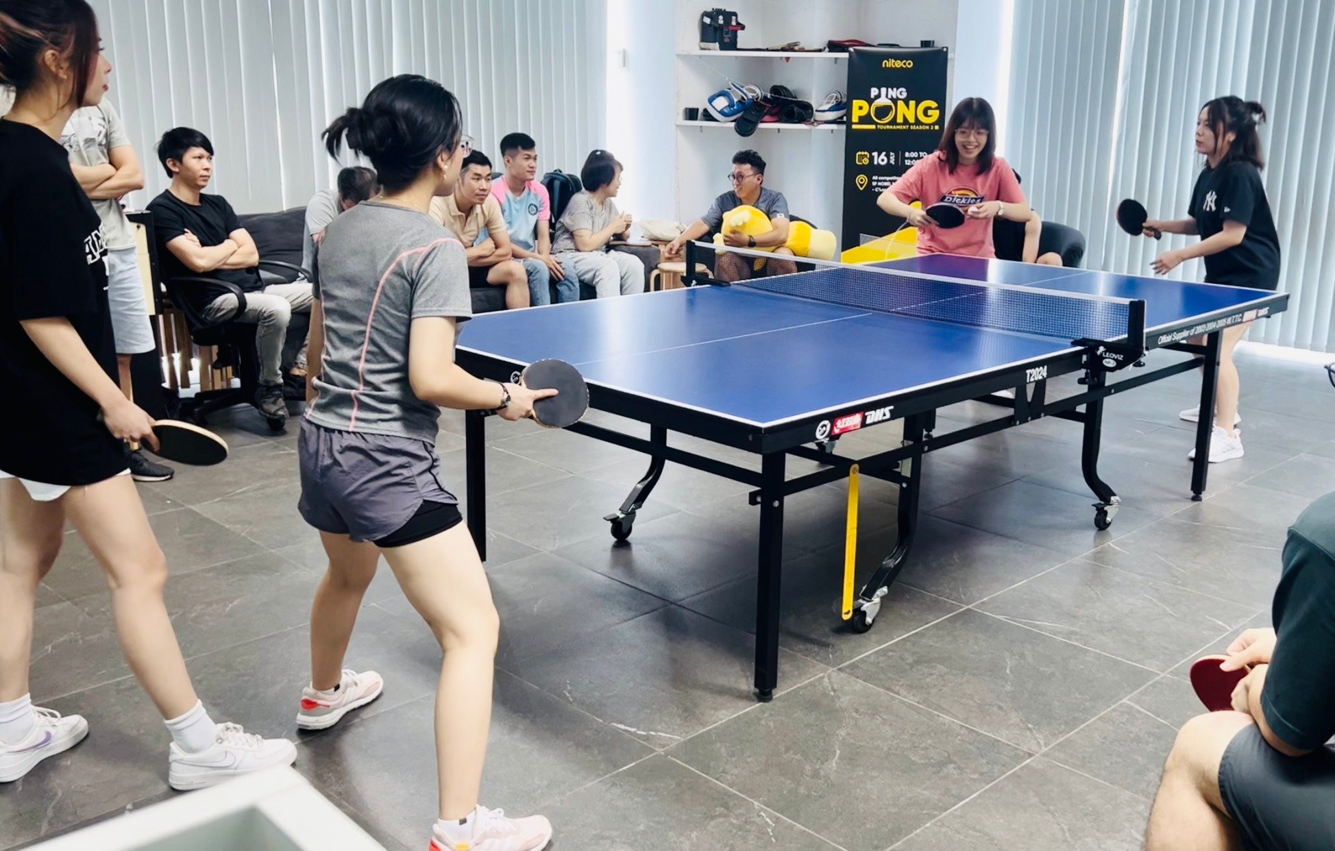 Young adults playing ping pong during an indoor table tennis tournament event