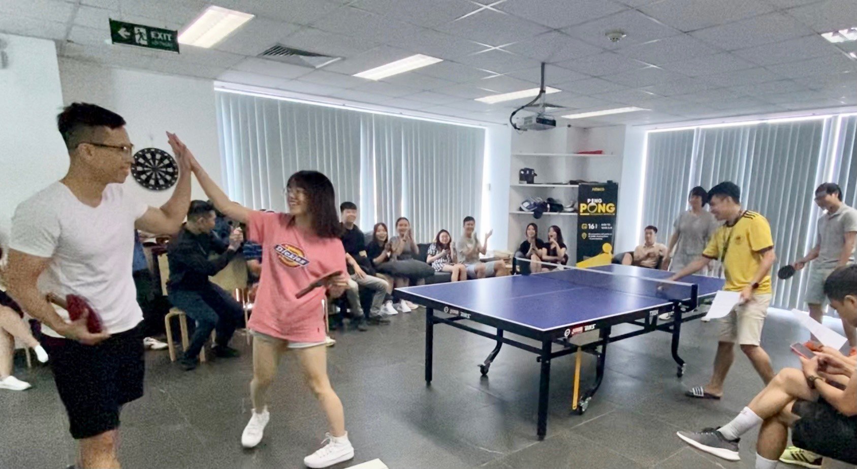 Office ping pong game with employees cheering and players high-fiving