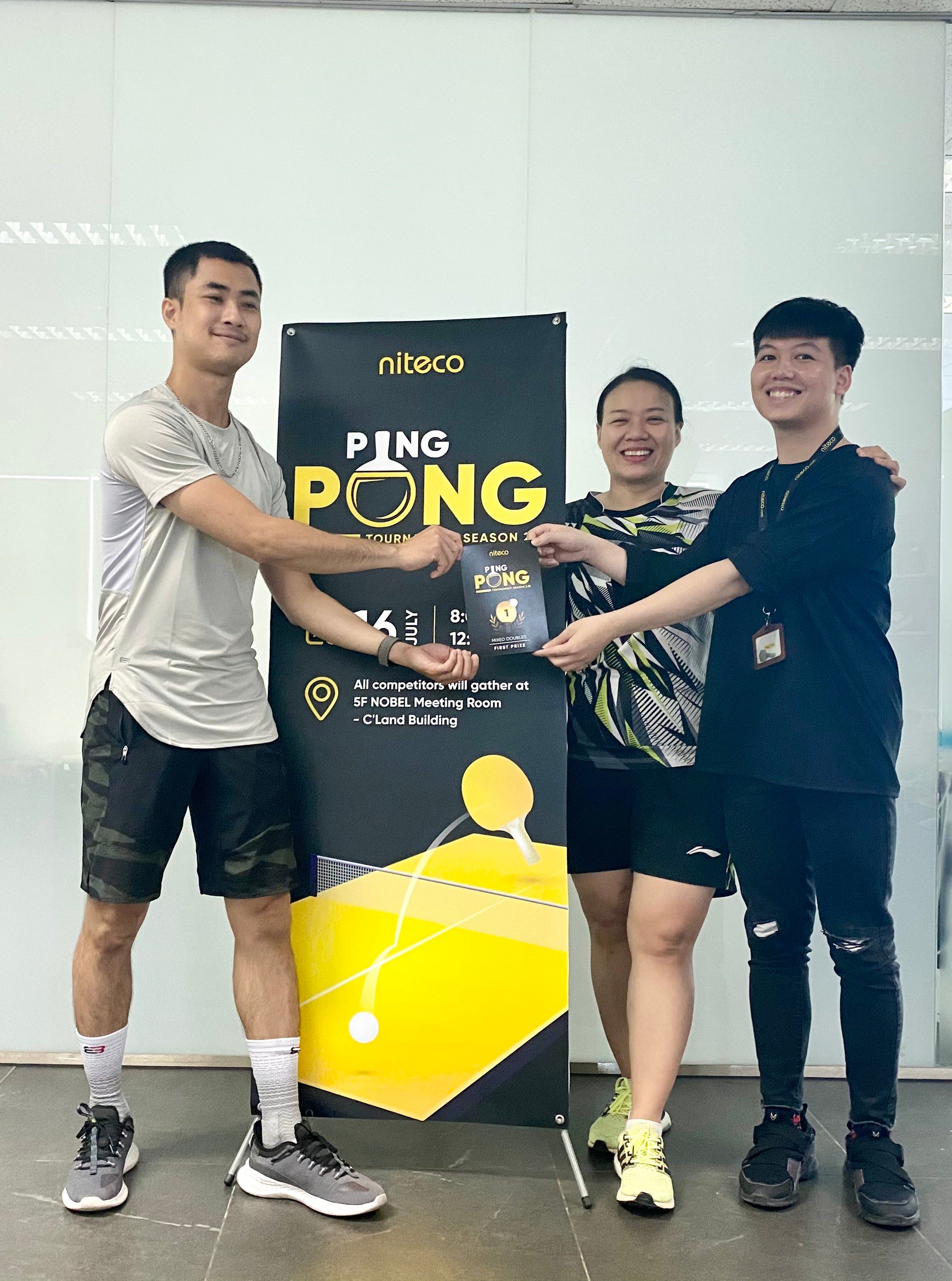 Three smiling winners holding first prize at Niteco Ping Pong Tournament event