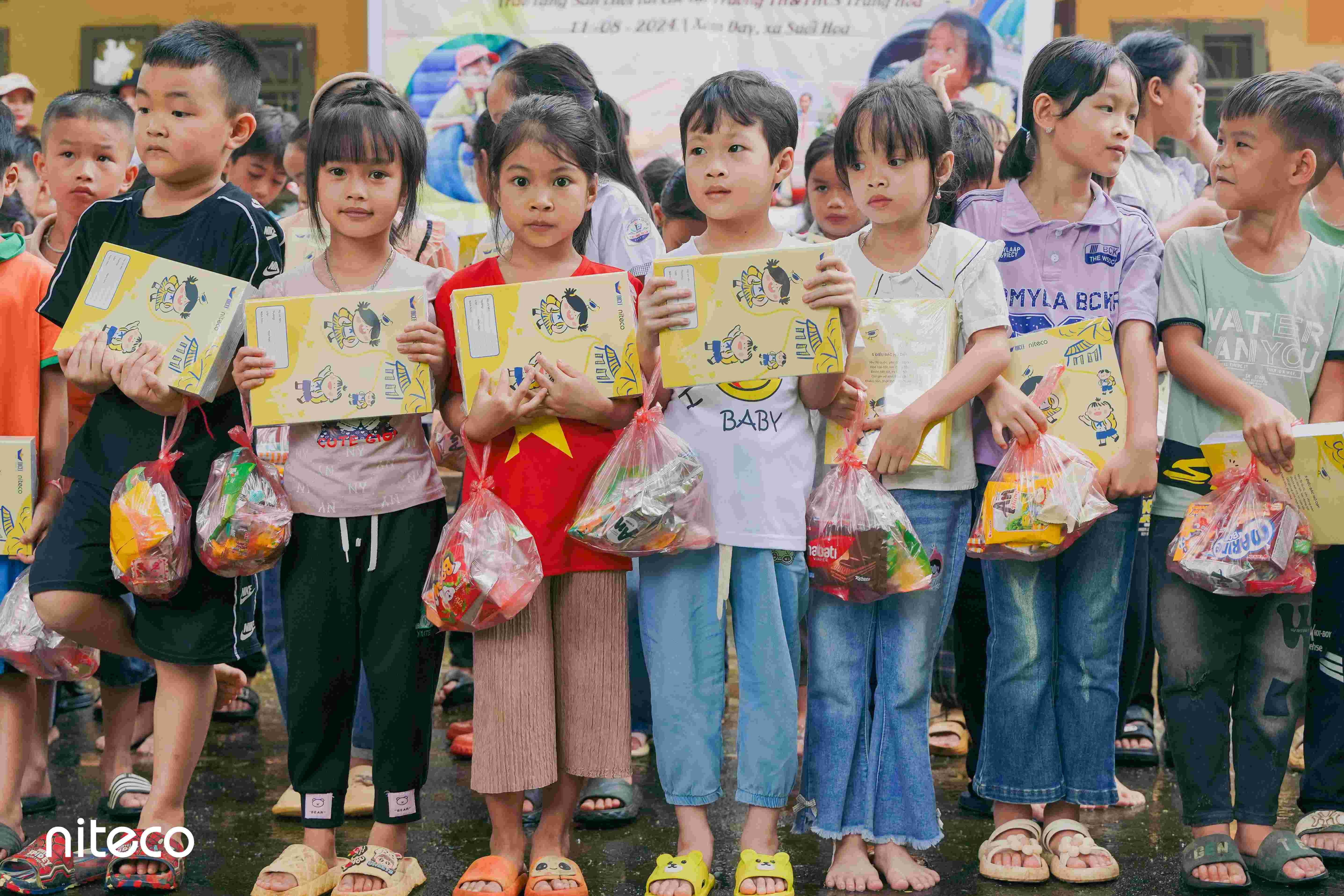 Children holding gifts and school supplies during community charity event