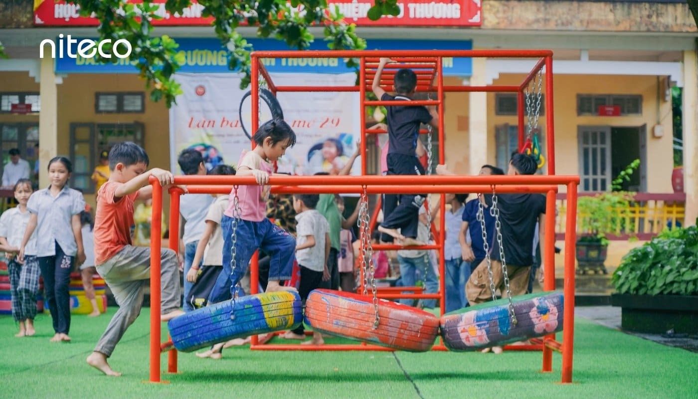 Children playing on colorful tire swing set in outdoor school playground
