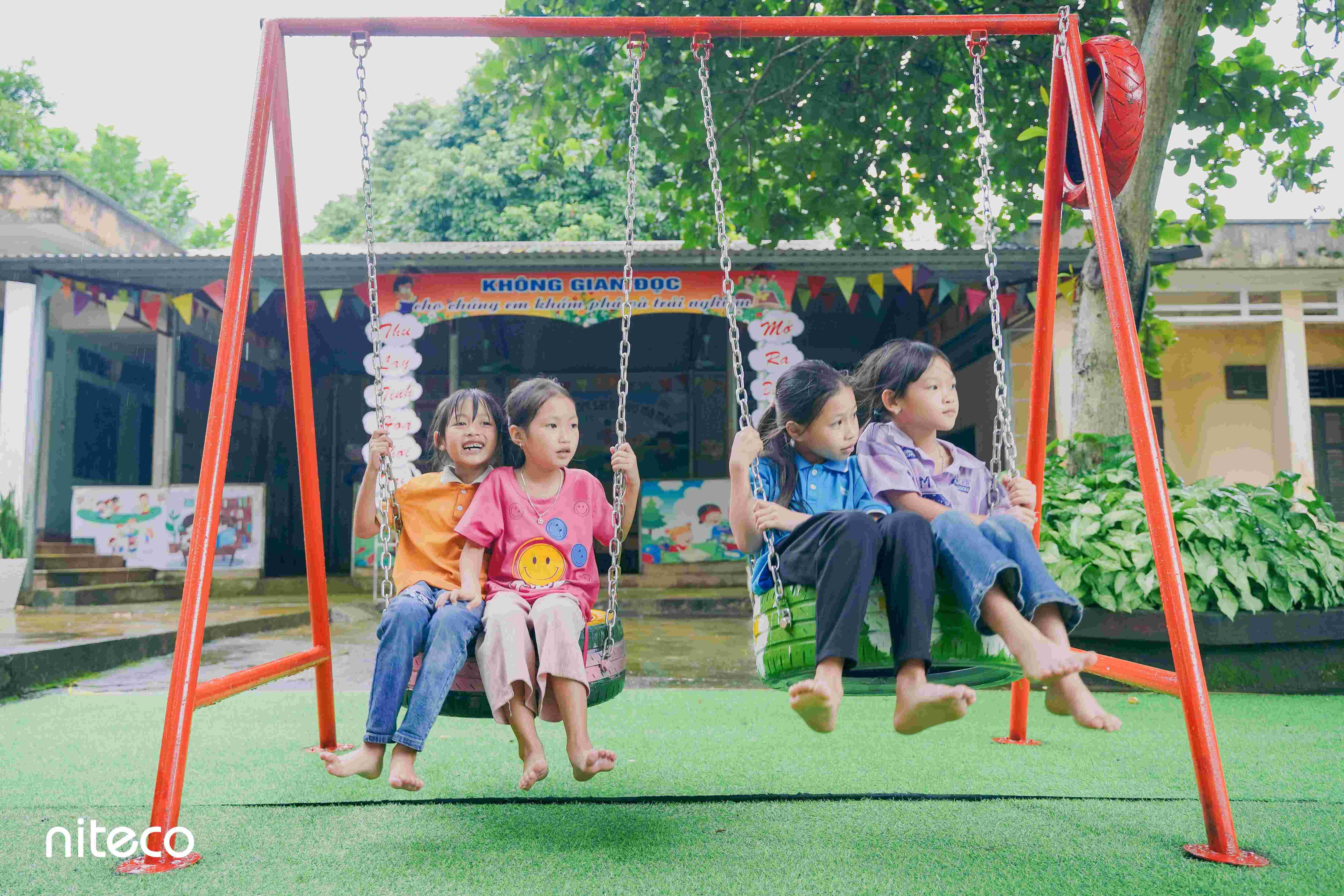 Four children enjoying playground swings in a vibrant outdoor setting