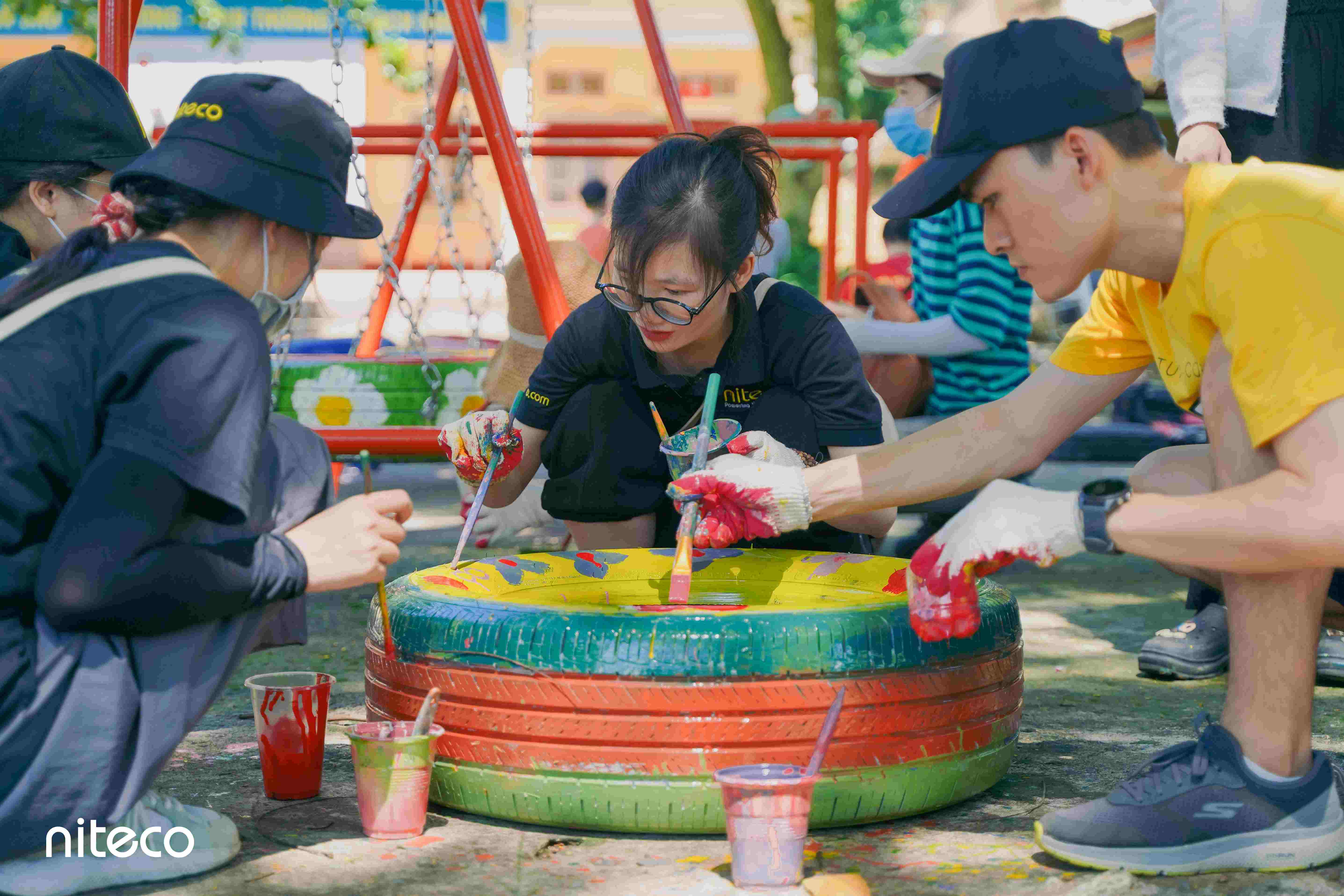 Volunteers painting colorful recycled tires for community environmental activities