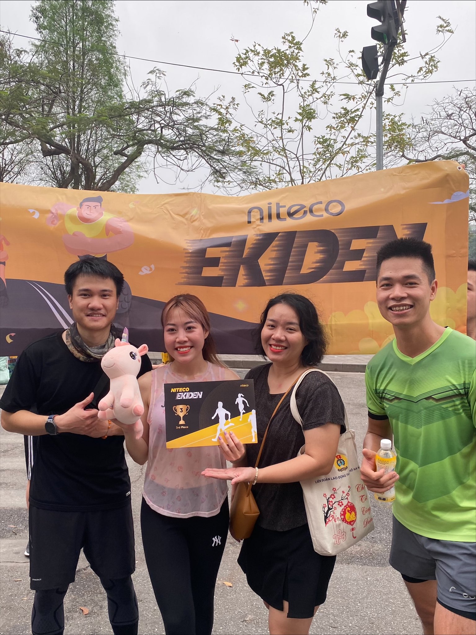 Niteco Ekiden team celebrating third place with trophy and mascot outdoors
