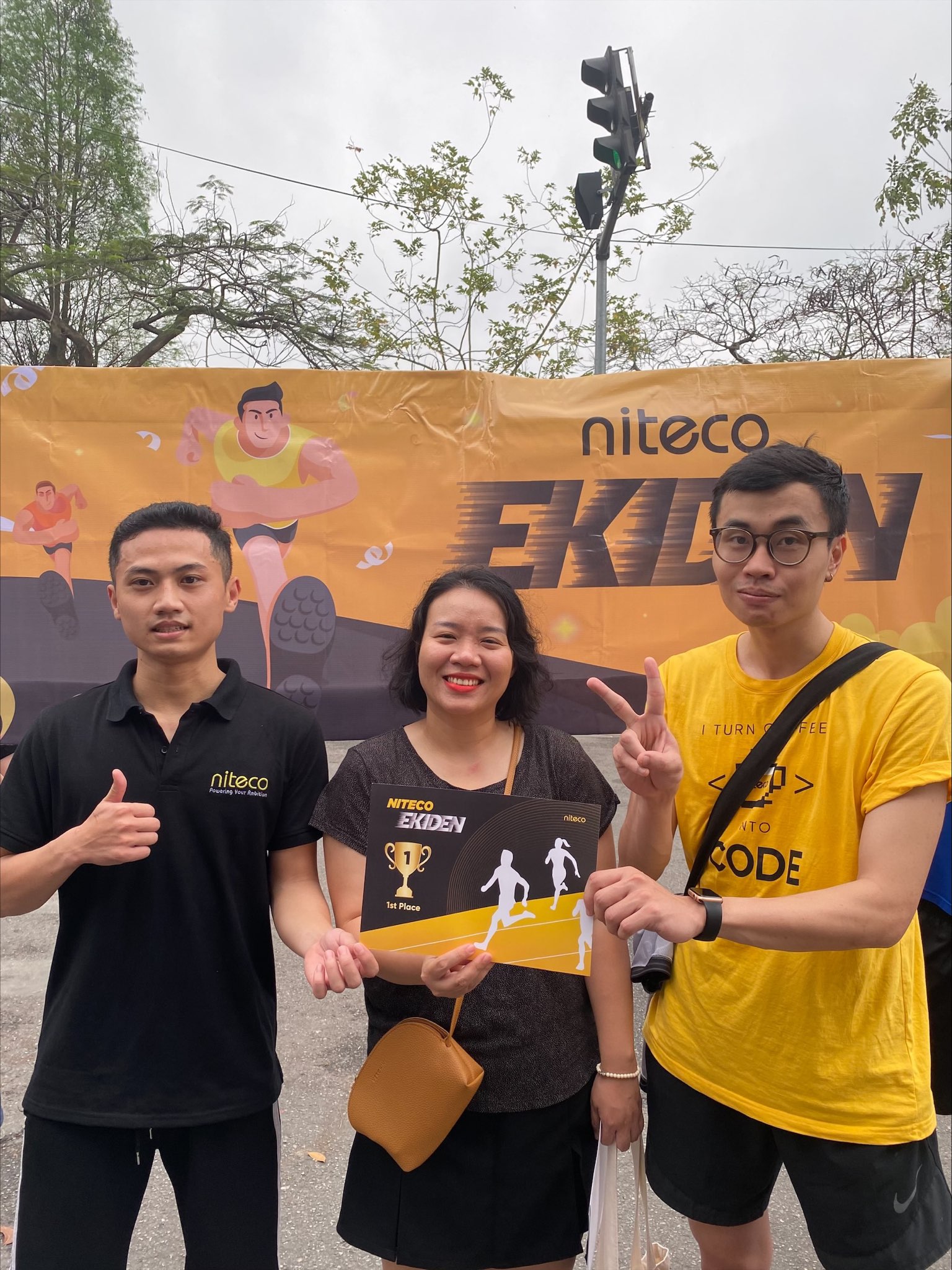 Three Niteco Ekiden event participants hold a 1st Place certificate outdoors.