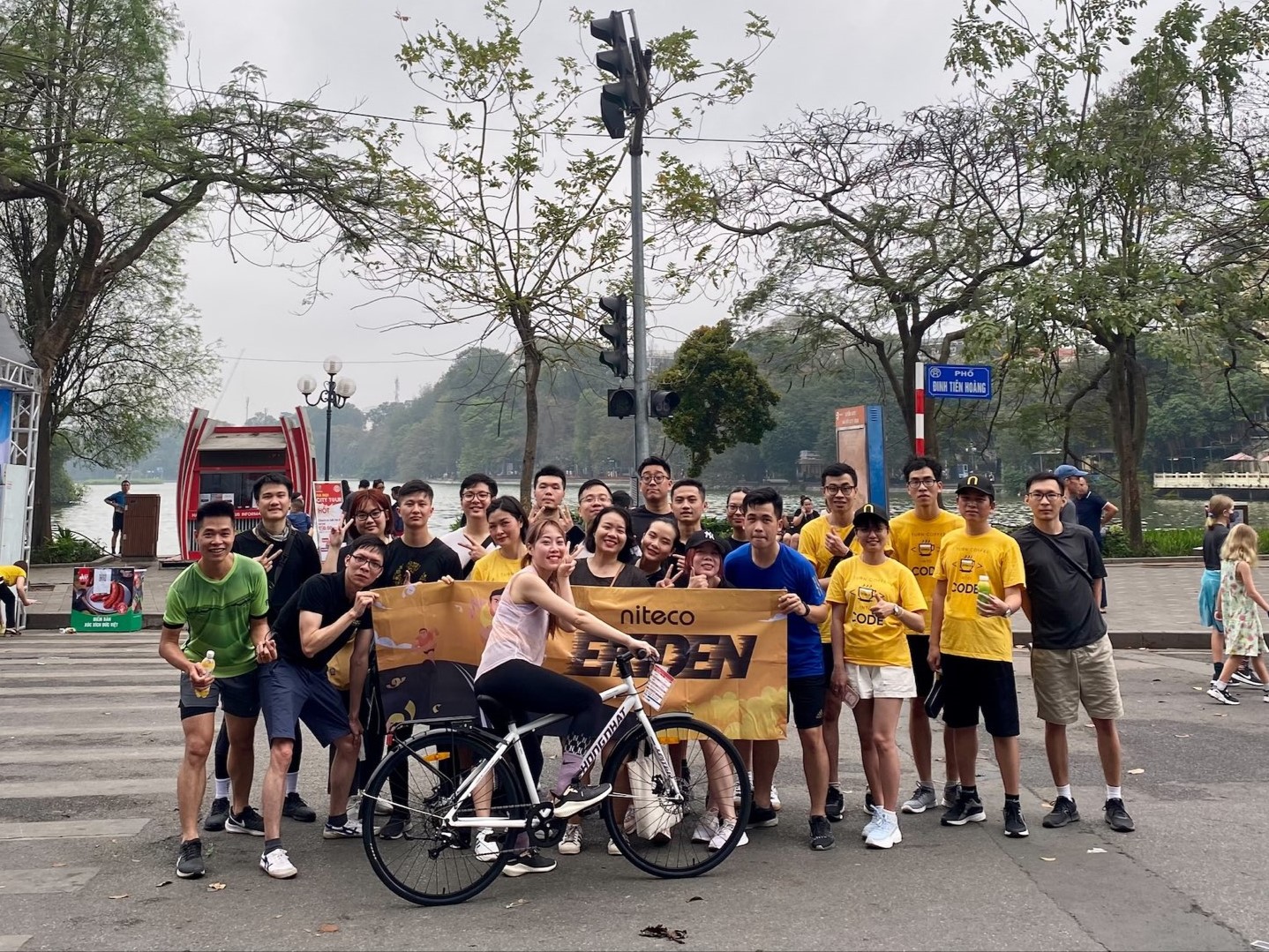 Niteco Fun Run group in bright yellow shirts with cyclist and banner outdoors
