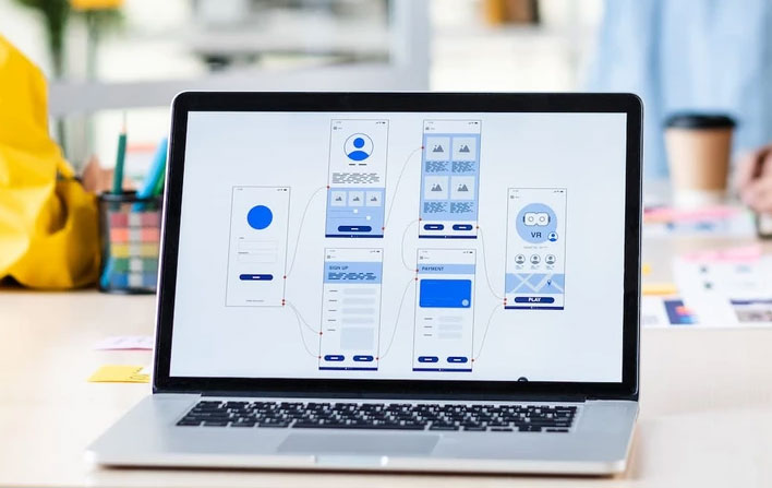 Laptop screen displaying mobile app wireframe and UI flow designs for user experience.