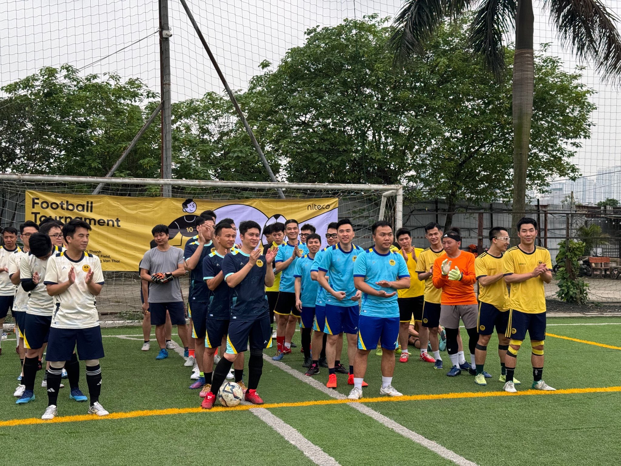 Football tournament players lined up on field clapping before match kickoff