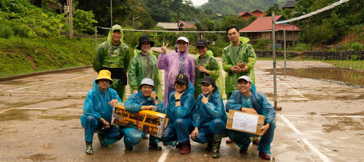 Group wearing rain ponchos posing outdoors with toys and gifts, community event