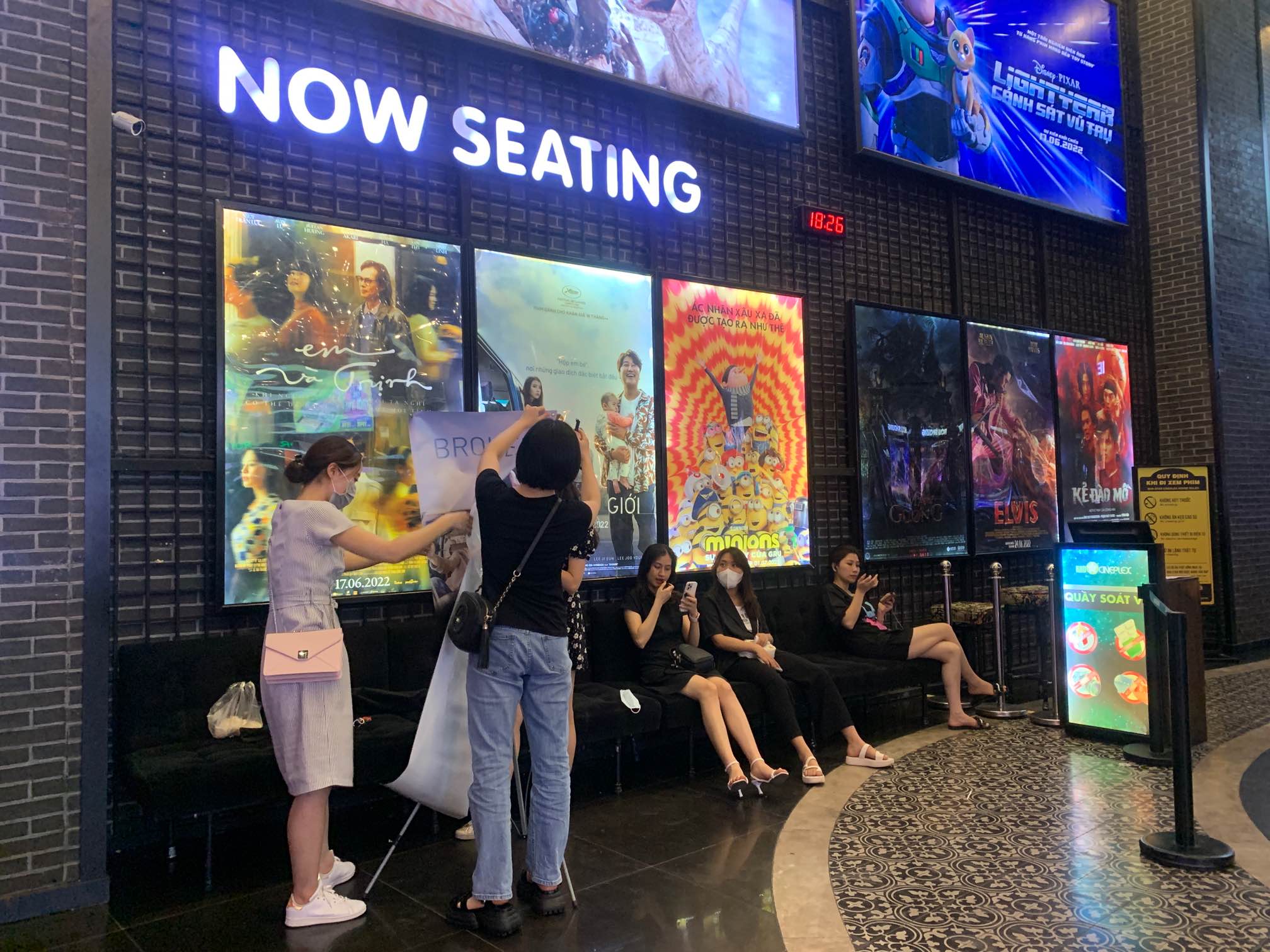 Cineplex now seating area with movie posters and people waiting in lobby