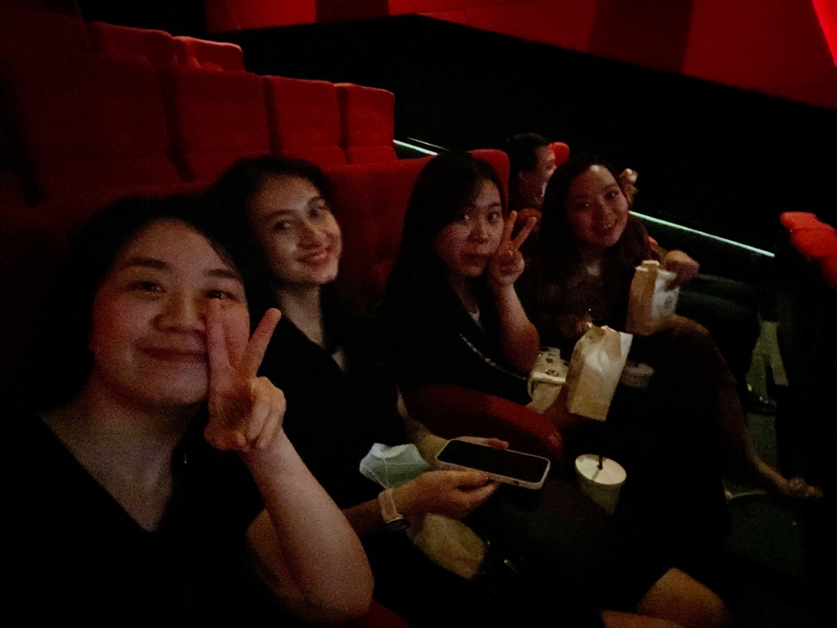Friends enjoying movie night in a theater with popcorn and drinks