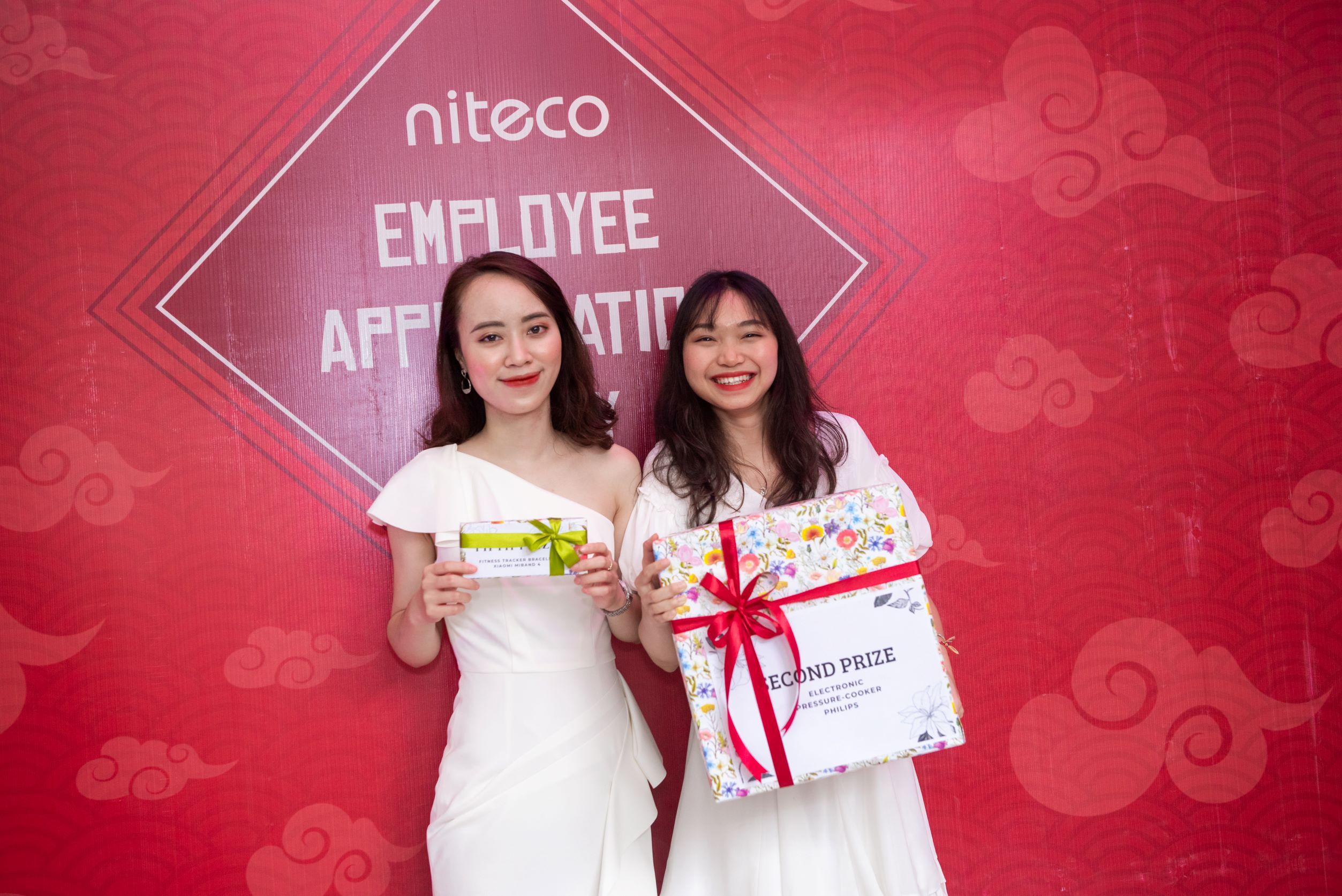 Two employees smiling with prizes at Niteco employee appreciation day event