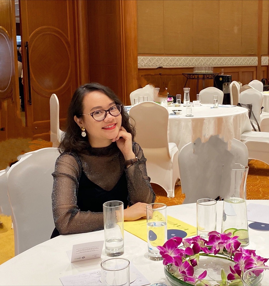 Woman smiling at conference table with purple orchids and water glasses
