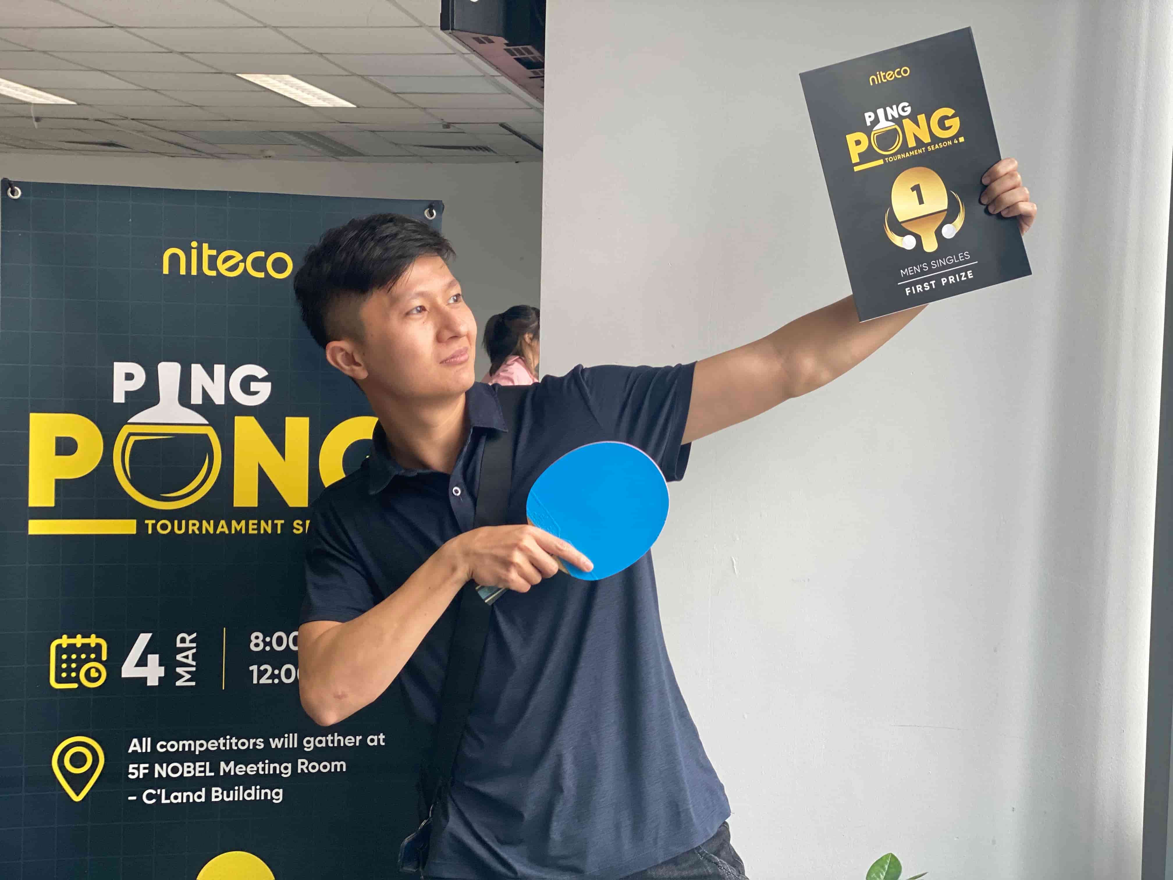 Man holding ping pong paddle and first prize certificate at Niteco tournament