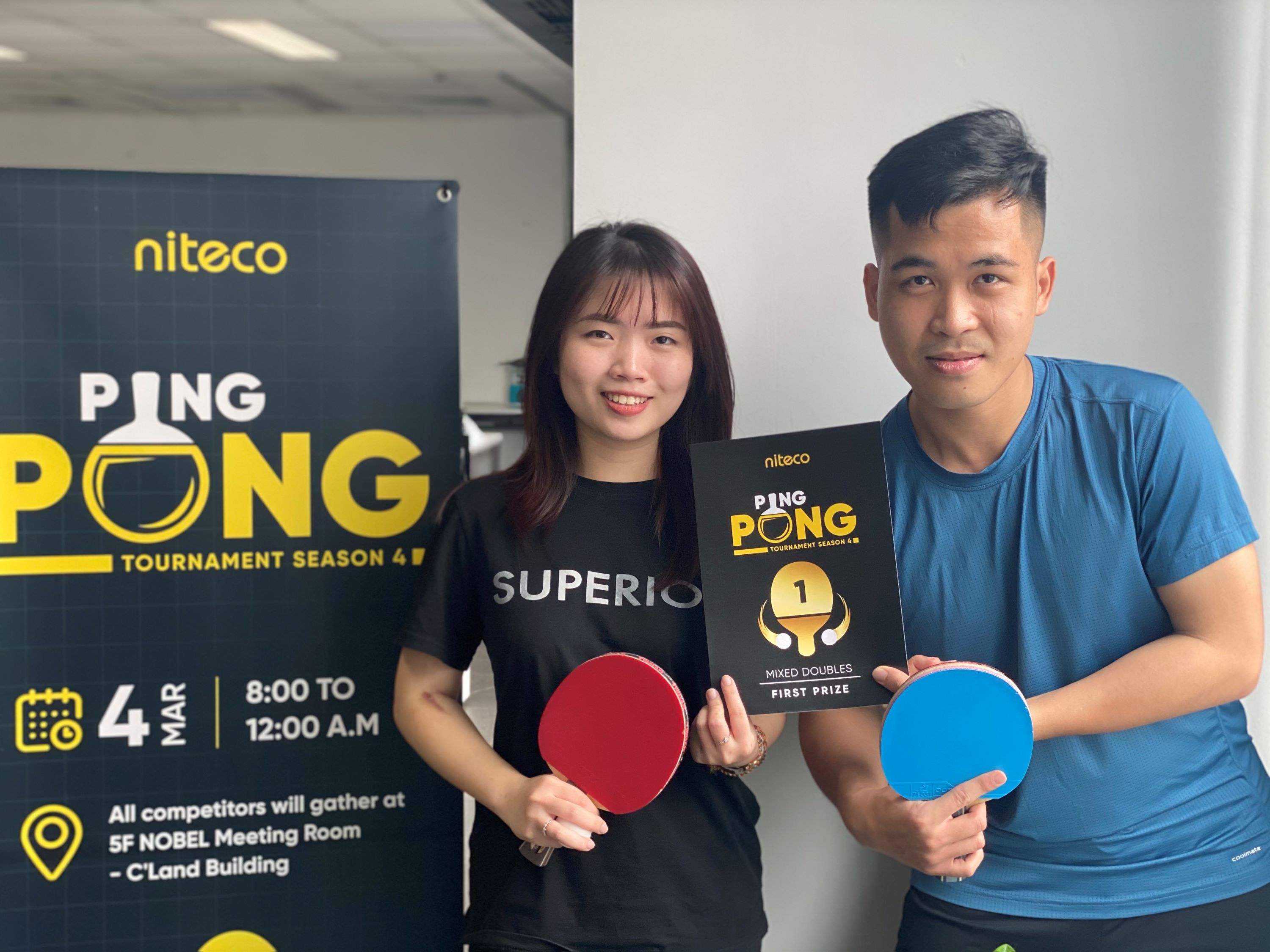 Winners holding first prize award and paddles at Niteco Ping Pong Tournament