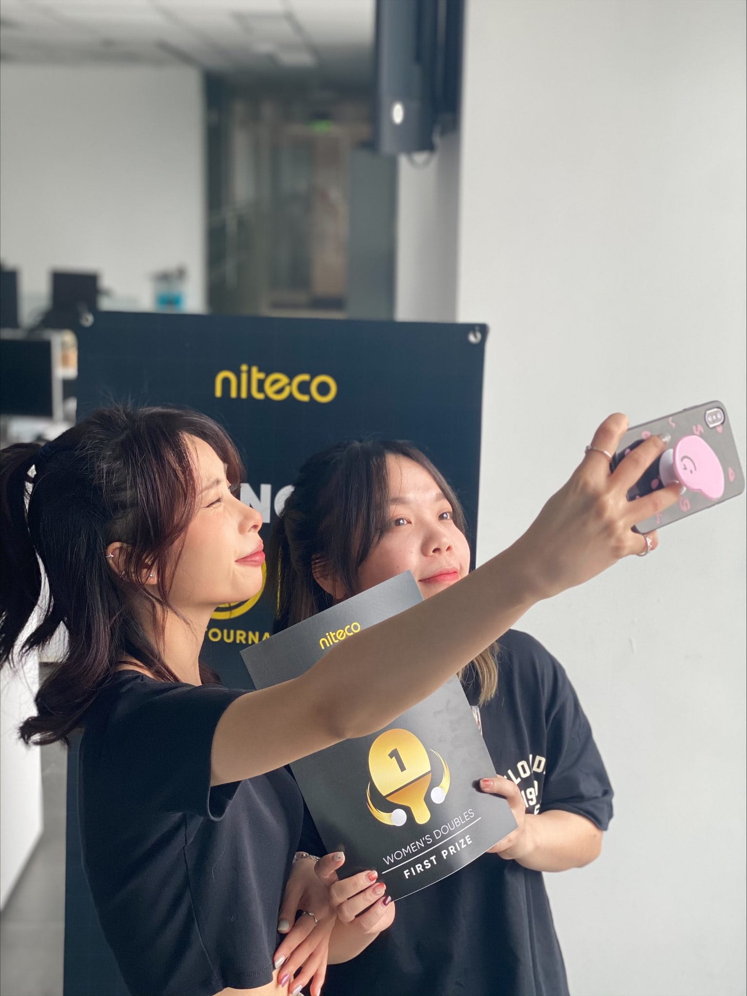 Two women taking selfie with niteco Women's Doubles first prize certificate