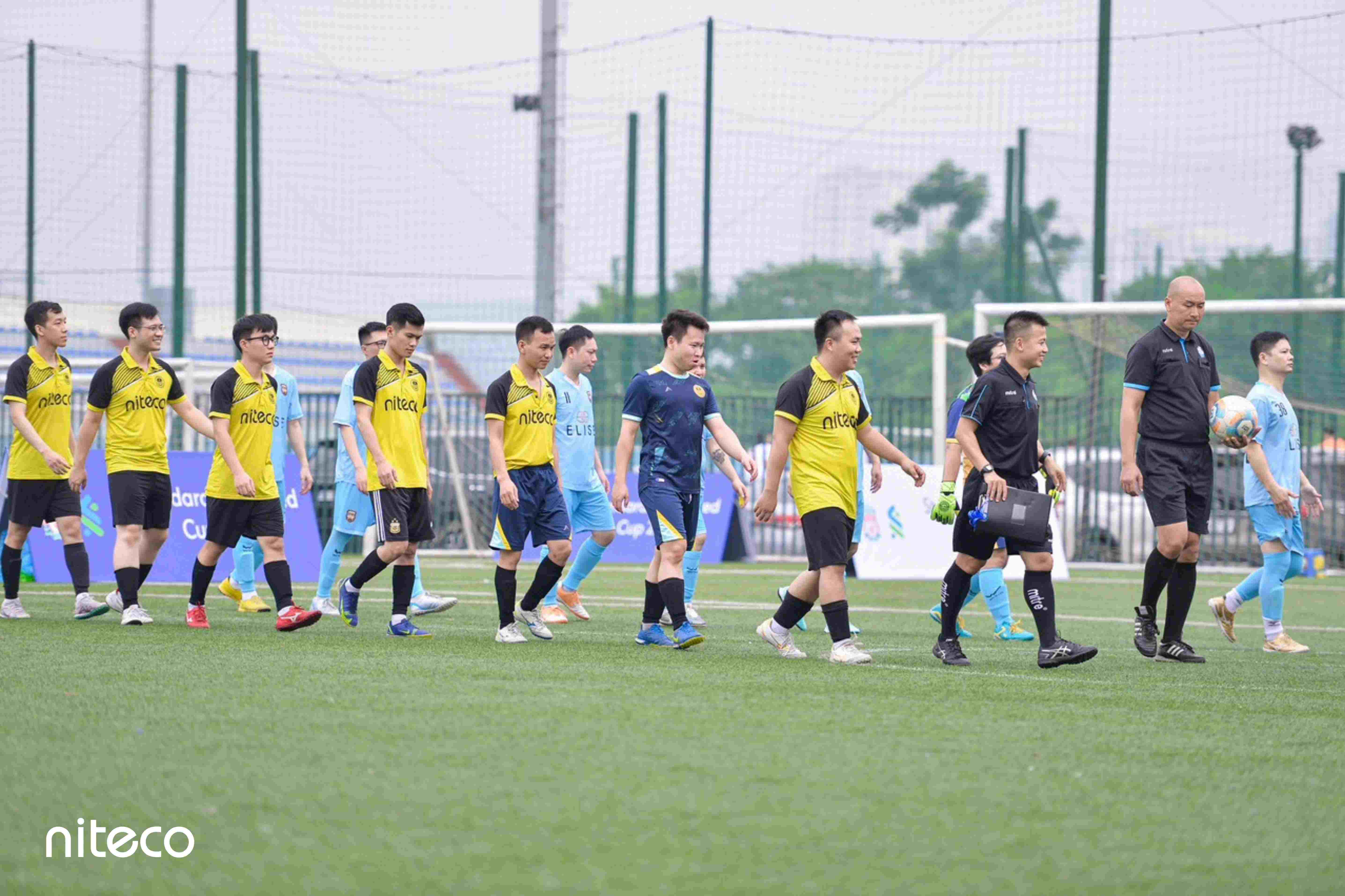 Niteco football team and referees walking on soccer field before match