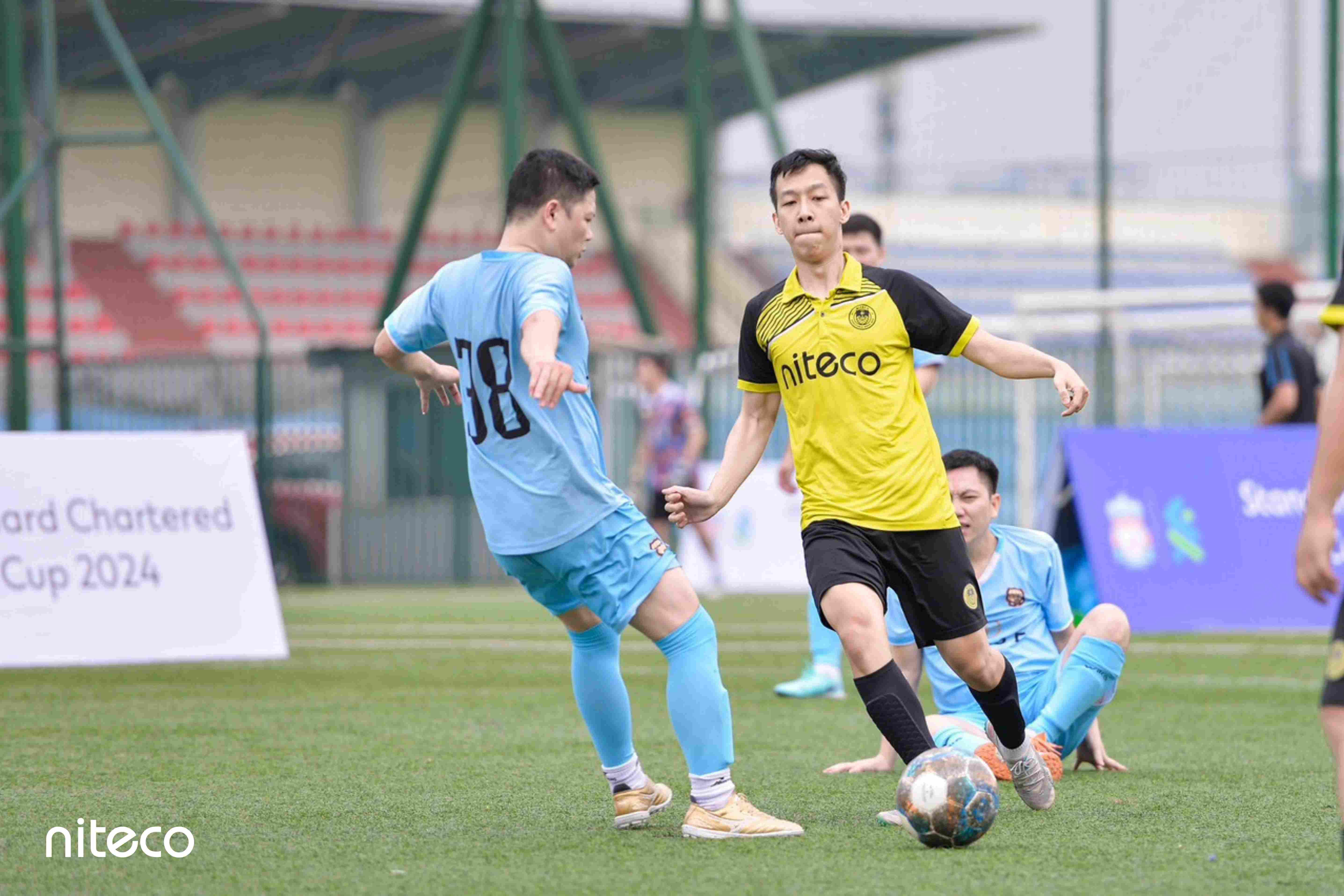 Niteco soccer players competing for ball during Standard Chartered Cup 2024 match