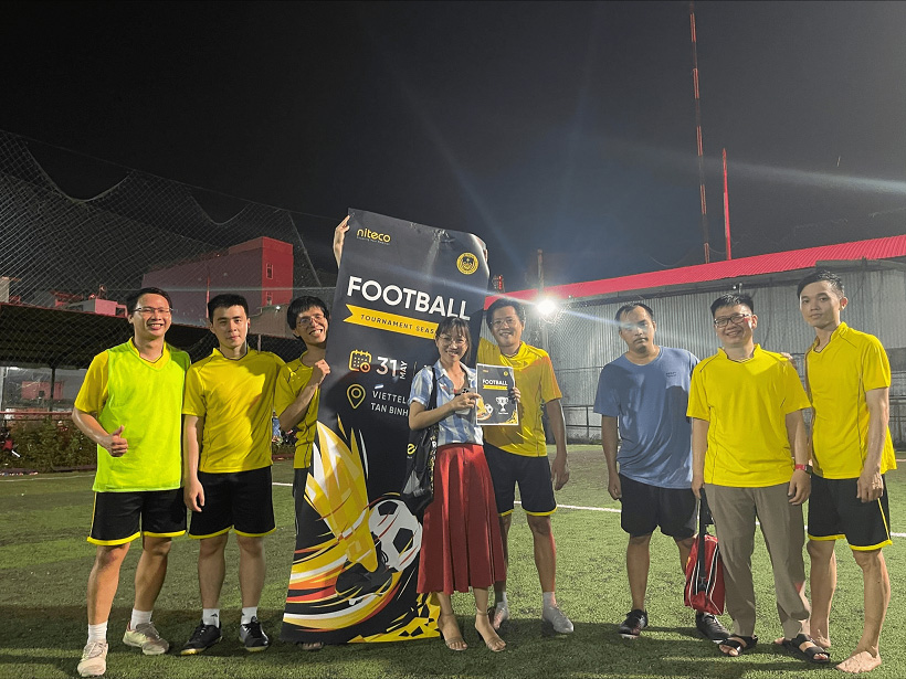 Football tournament team celebrating with trophy and banner on Viettel field