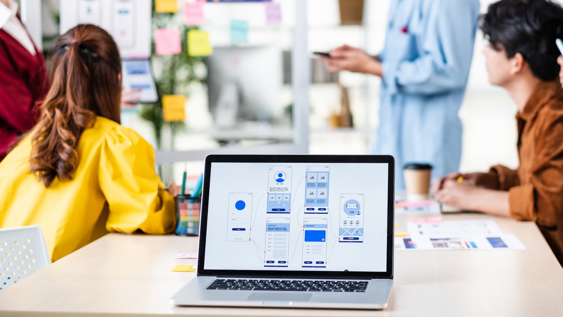 Laptop displaying app wireframe design during team mobile app development meeting
