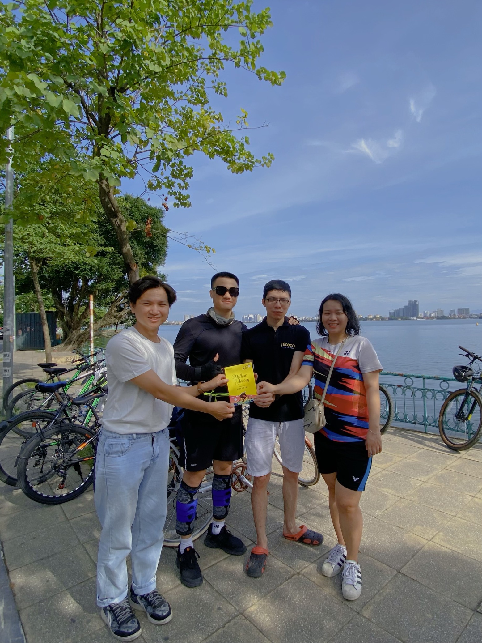 Group of cyclists by lakeside holding Yellow Jersey cycling award outdoors