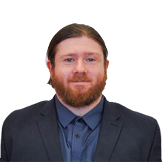 Professional headshot of a man with red hair and beard in a suit and blue shirt