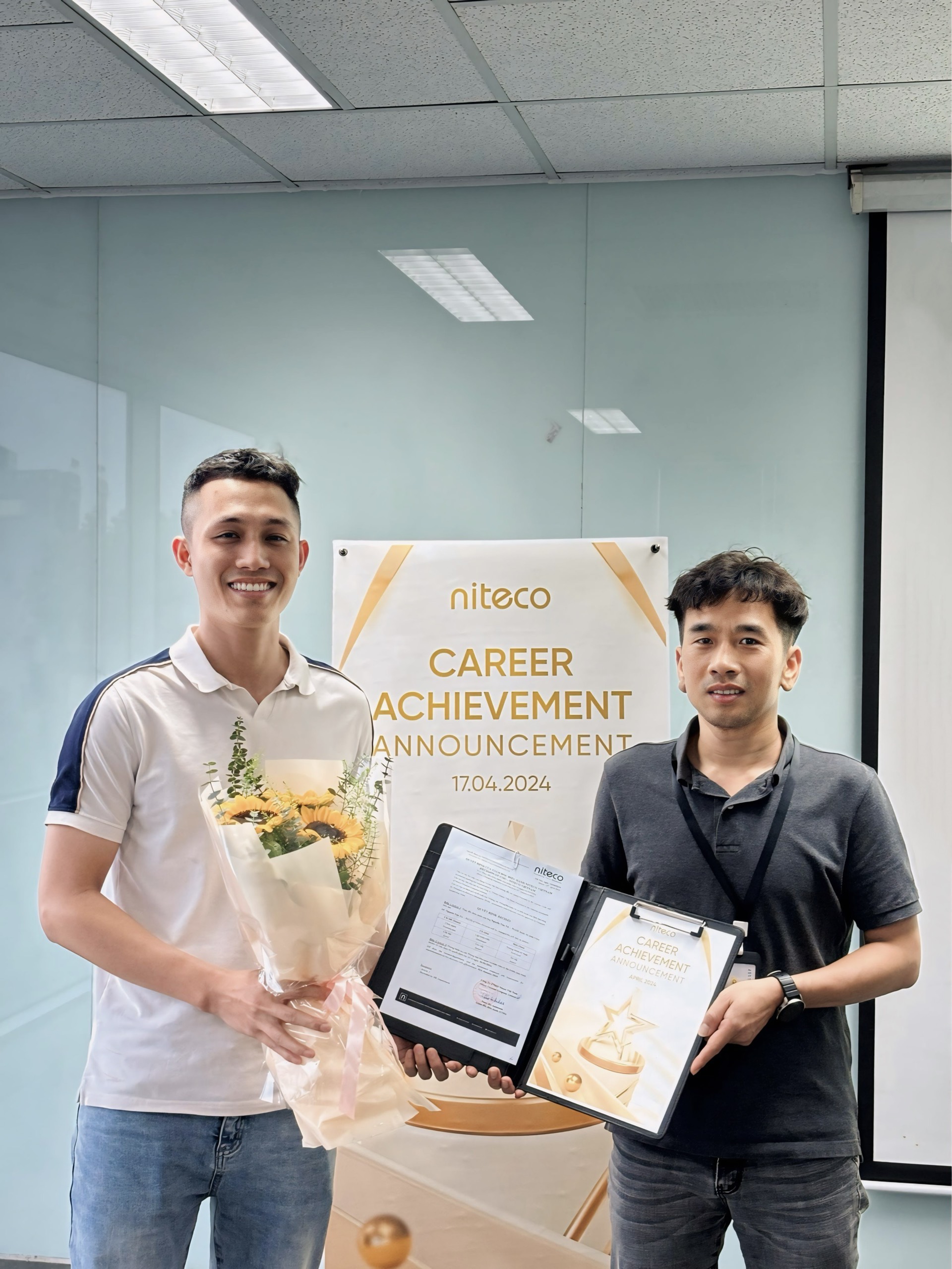 Niteco career achievement announcement with employee holding flowers and certificate