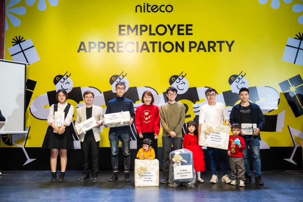 Employees with prizes at Niteco Employee Appreciation Party on yellow backdrop