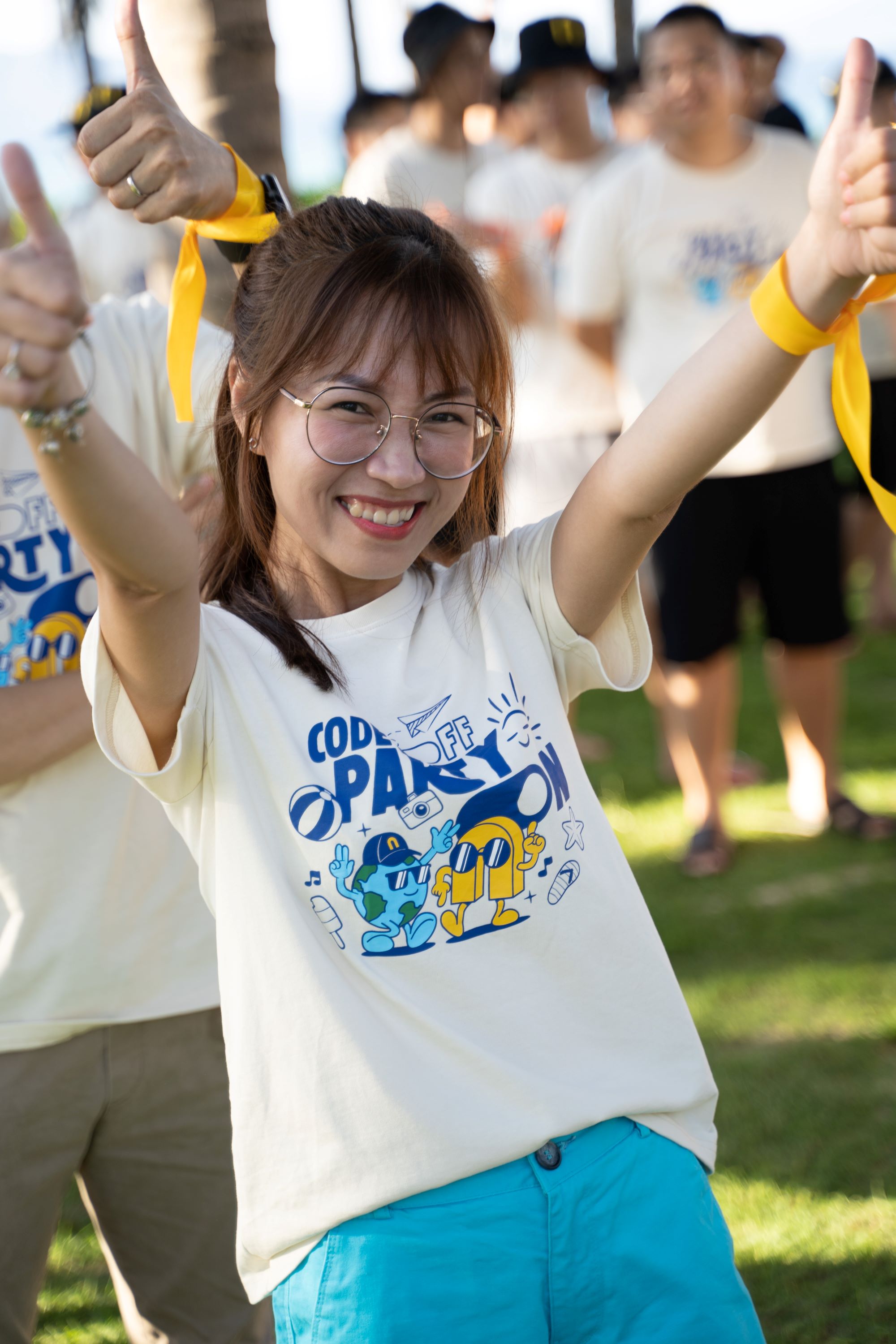 Smiling woman with glasses wearing a Code Off Party t-shirt giving thumbs up