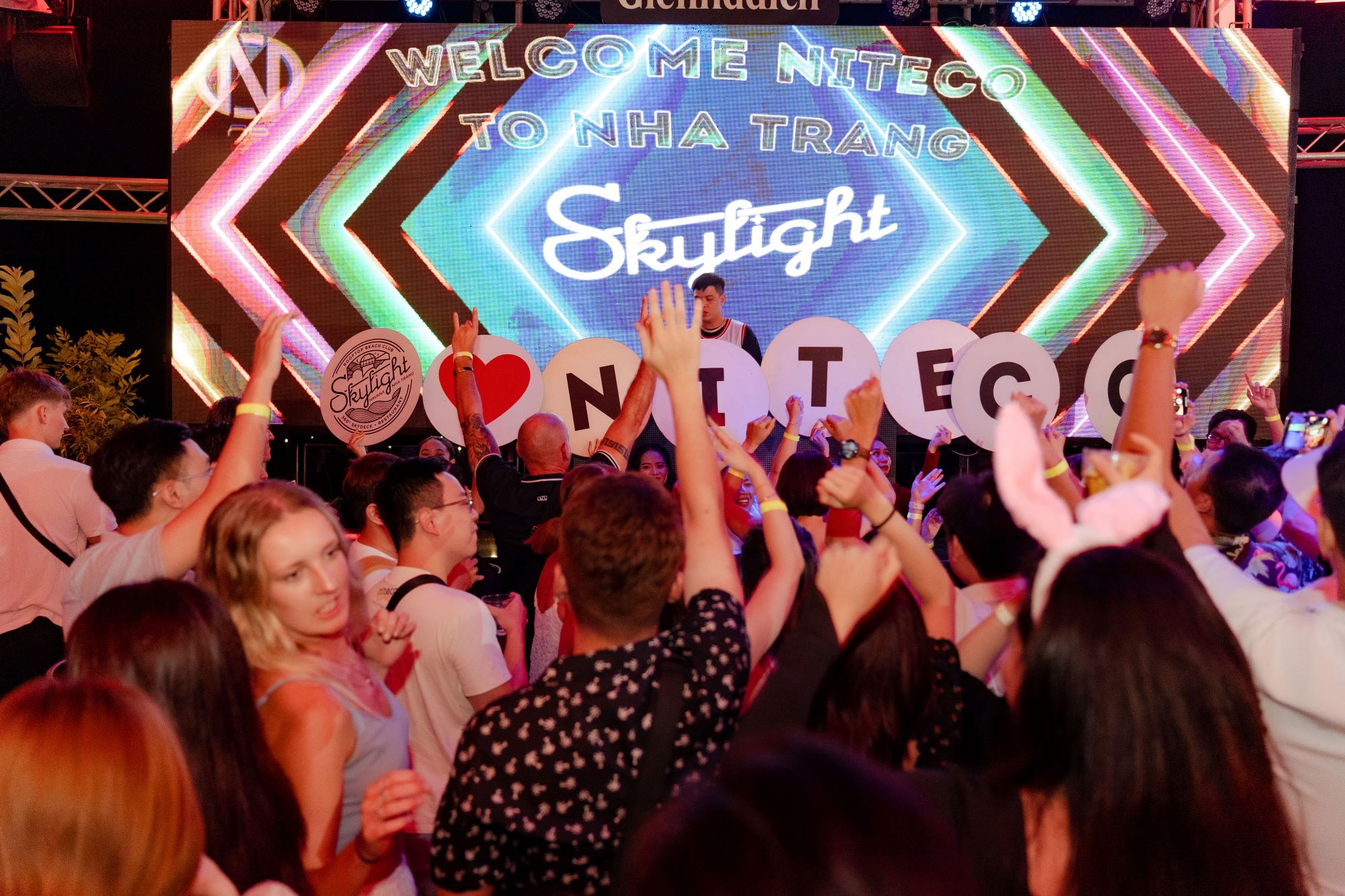Crowd celebrating at Skylight nightclub in Nha Trang with NITECO signs raised