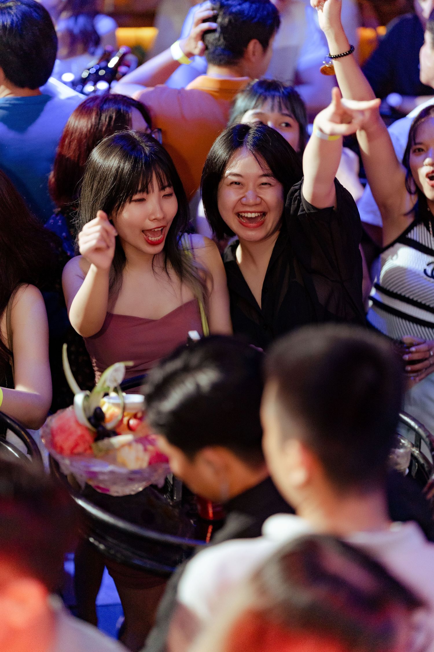 Two young women enjoying nightlife party with drinks and dancing energy