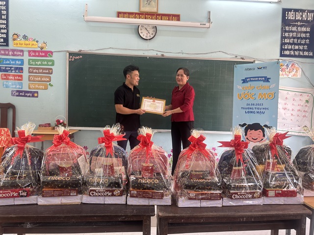 Teachers exchanging certificate during Chắp Cánh Ước Mơ gift event at Long Hậu school