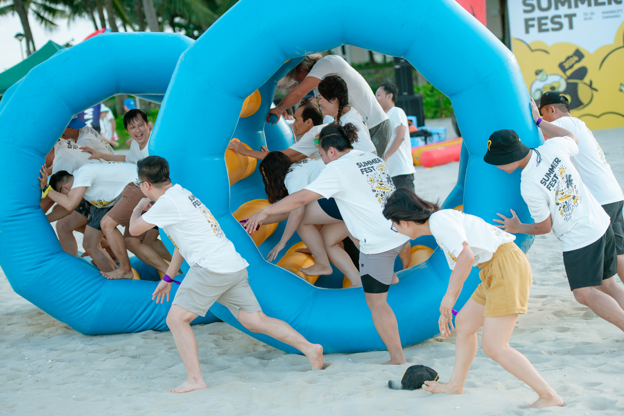 Group playing team-building games with inflatable wheels at Summer Fest beach event