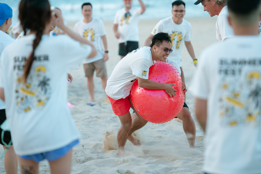 Young man playing beach games with inflatable ball during summer festival event