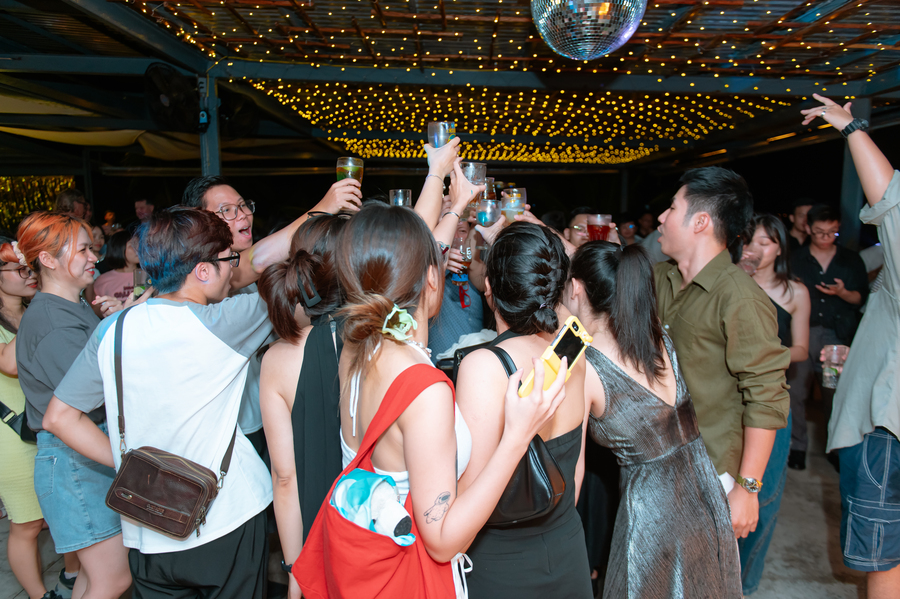 Friends celebrating with drinks under string lights and a disco ball at party