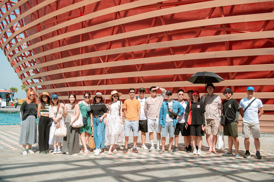 Group of tourists posing in front of a large wooden architectural structure