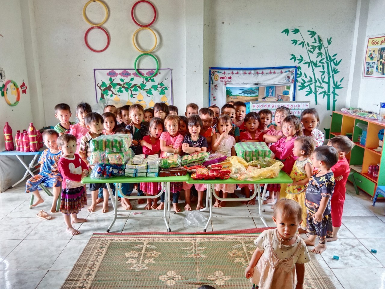Group of young children gathered around a table with food packages in classroom