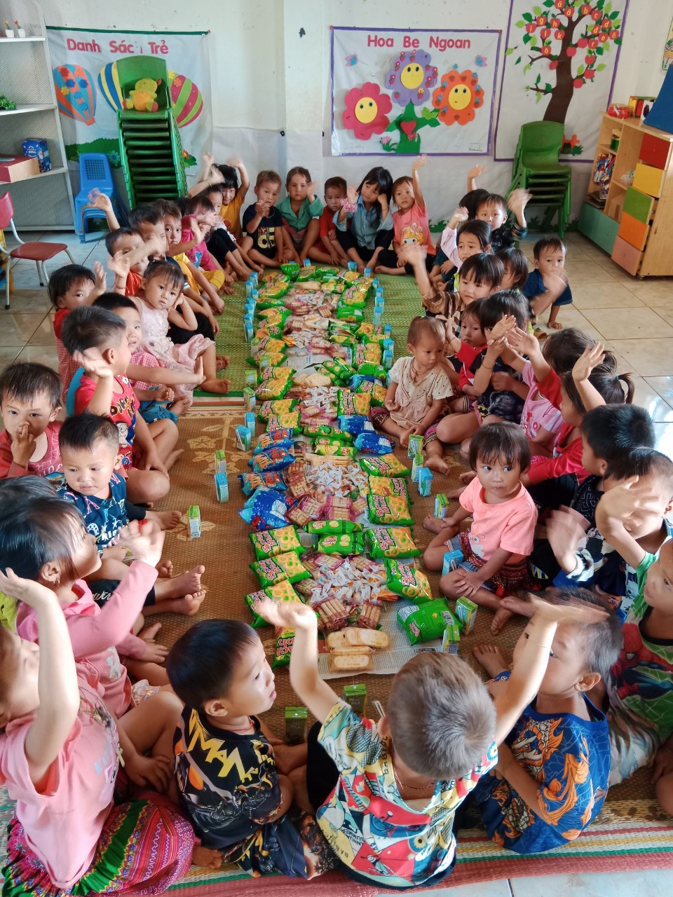 Preschool children in classroom sitting around snacks and juice boxes on mat