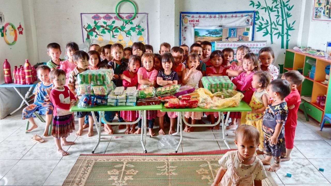 Children receiving food and supplies in a classroom charity donation event