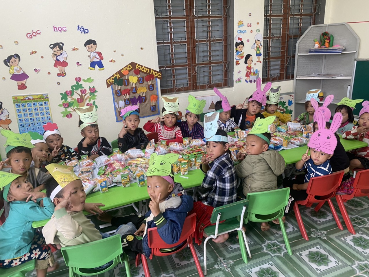Children wearing animal hats enjoying snacks in a colorful classroom setting
