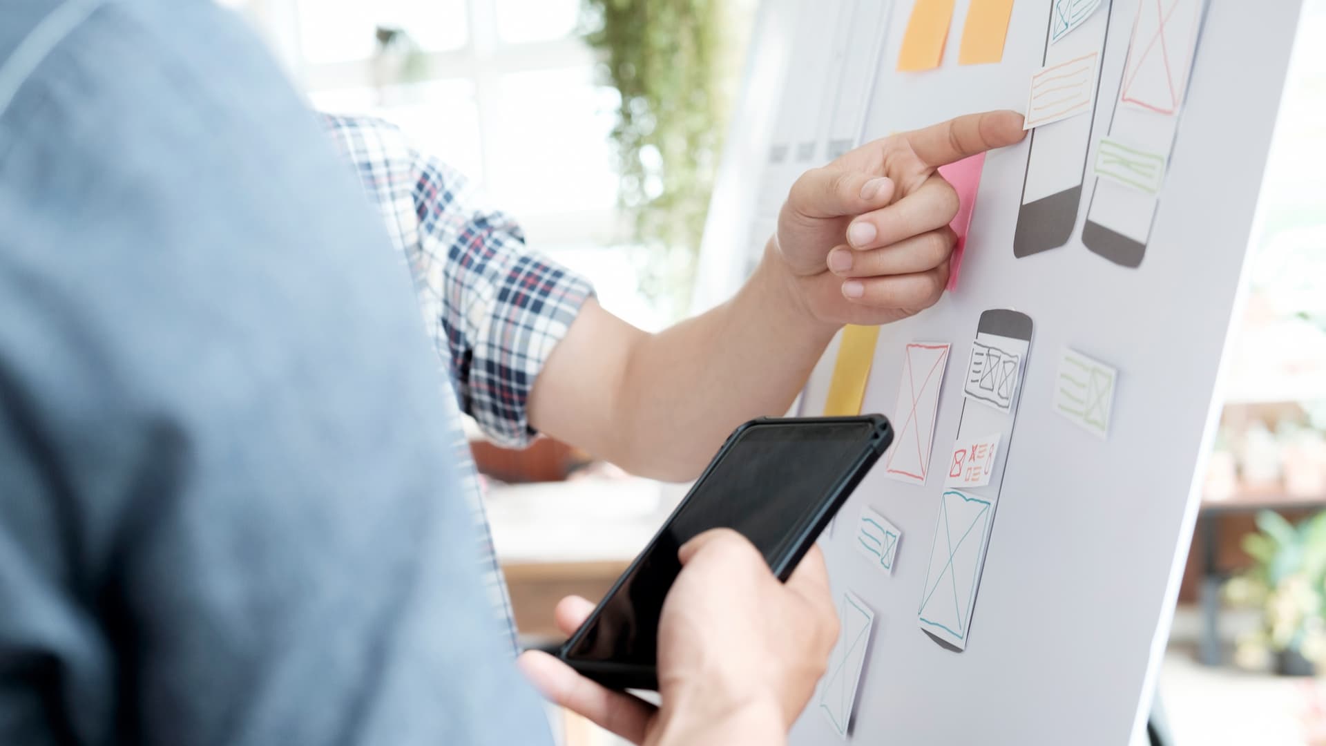 Mobile app wireframe planning with smartphone and user interface sketches on board