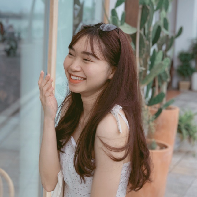 Smiling young woman with long hair enjoying a sunny day near plants