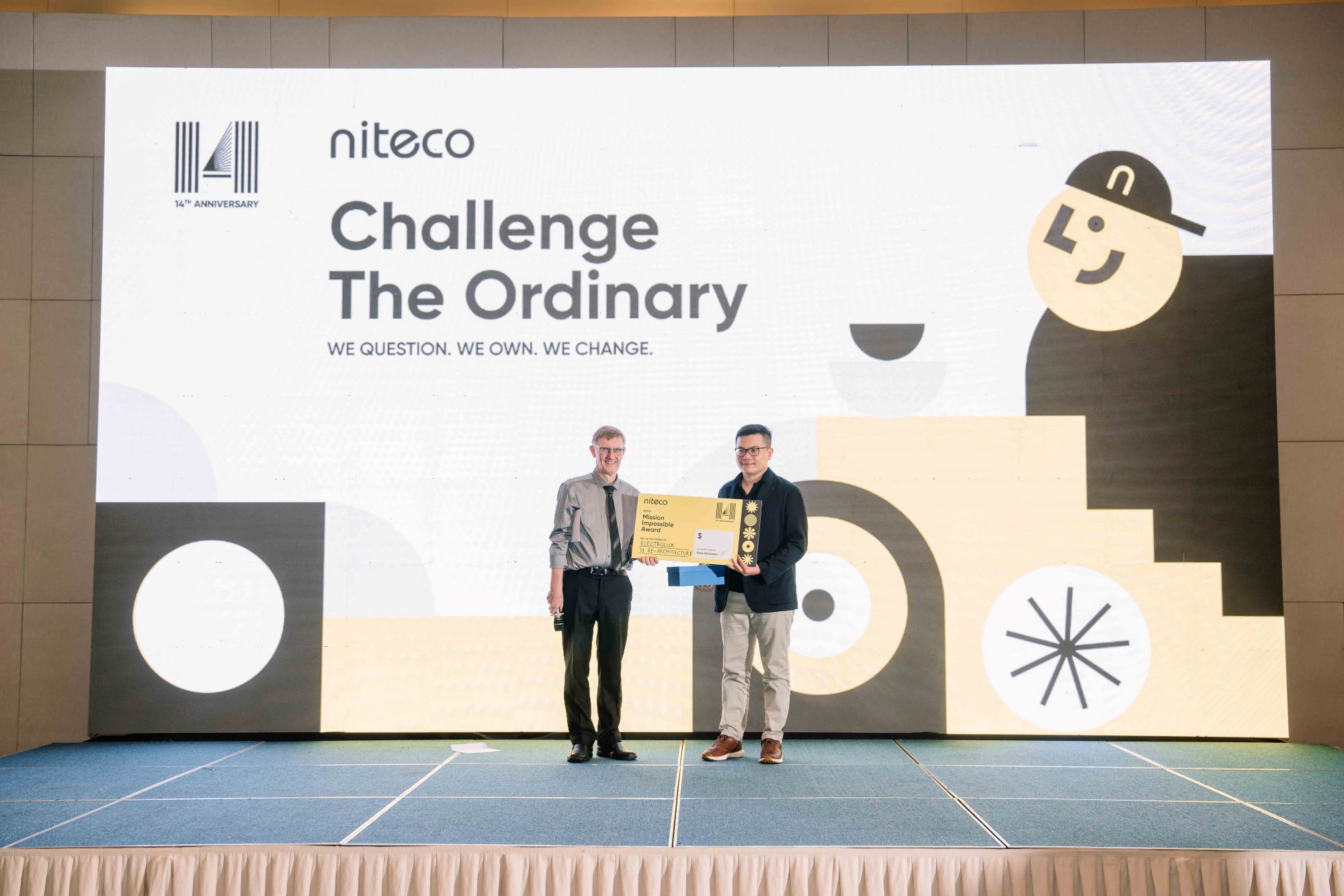 Two men holding award on stage at Niteco 14th anniversary Challenge The Ordinary event
