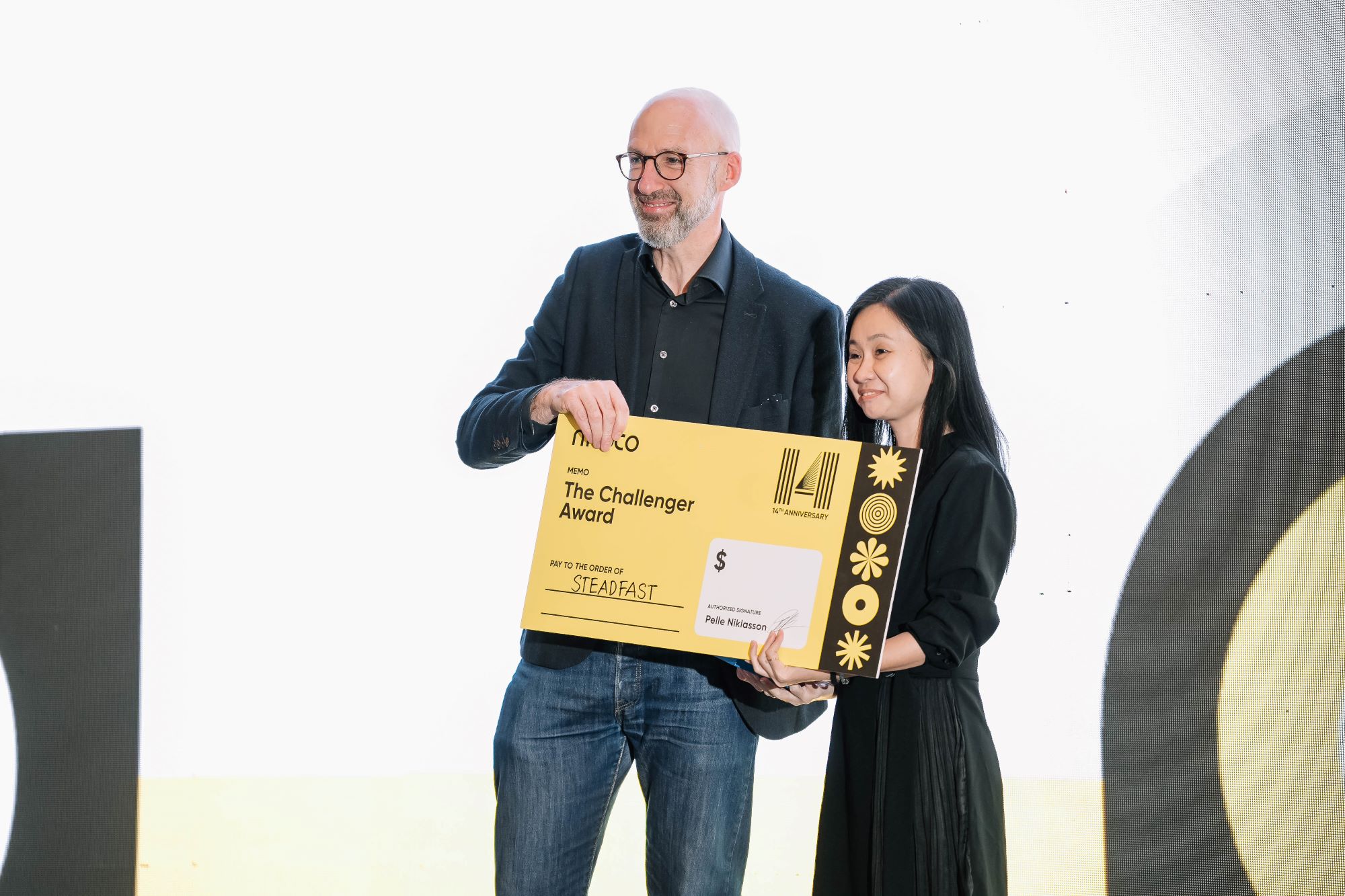 Man and woman holding The Challenger Award check for Steadfast at 14th anniversary event