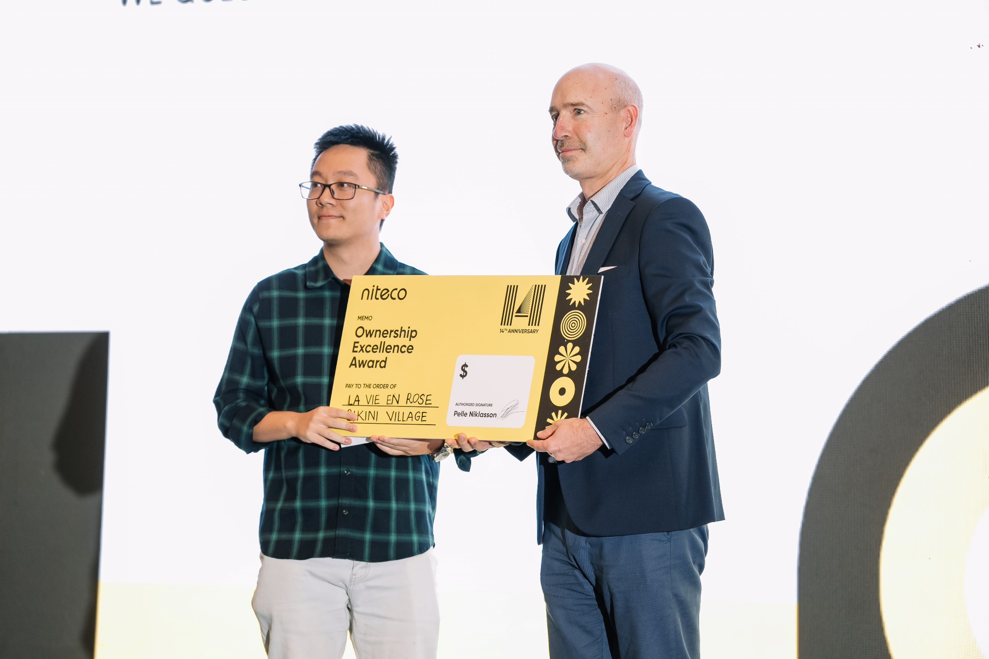 Two men holding the Ownership Excellence Award from Niteco 14th Anniversary event